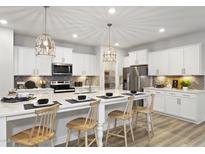 Bright kitchen features white cabinets, stainless steel appliances, and a large island with seating at 136 Willow Cameron Way, Angier, NC 27501