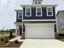 Charming two-story home featuring a white two-car garage, blue siding, and manicured landscaping at 136 Willow Cameron Way, Angier, NC 27501