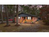 Charming brick home with a cozy porch and natural wood accents nestled among tall, mature trees at 1721 Fountain St, Rocky Mount, NC 27801