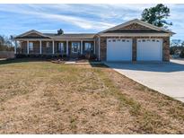 Charming brick home featuring a covered porch, two-car garage, and a well-maintained front yard at 2420 New Bethel Church Rd, Garner, NC 27529