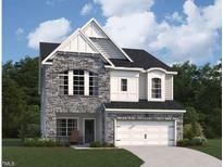 Charming two-story home featuring stone accents, a two-car garage, and a well-manicured lawn, creating an inviting curb appeal at 4404 Emeline Way # 35, Fuquay Varina, NC 27526