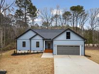 Charming single-story home showcasing a well-manicured lawn, a gray garage door, and light blue siding at 605 Shawnee Dr, Louisburg, NC 27549
