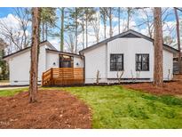 Charming home featuring white siding, black trim, wood deck, and beautifully manicured lawn at 1122 Shadyside Dr, Raleigh, NC 27612