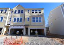 Two-story light yellow home with a two-car garage awaiting completion against a bright blue sky at 2317 Bay Minette Station Sta # 545, Apex, NC 27502