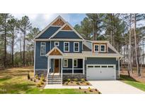 Beautiful two-story home featuring blue siding, a stone foundation, covered porch, and an attached two-car garage at 270 Purslane Dr, Franklinton, NC 27525