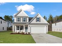 New two-story home featuring a well-manicured lawn, gray siding, black shutters, and a two car garage at 617 Spellbrook Rd, Zebulon, NC 27597