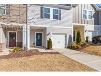 Charming gray two-story townhome with a one-car garage and a welcoming blue front door with seasonal wreath at 907 Field Ivy Dr, Fuquay Varina, NC 27526