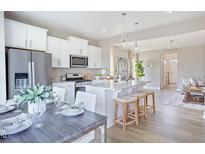 Bright, open kitchen with white cabinets, stainless steel appliances, and an island with seating at 97 Willow Cameron Way, Angier, NC 27501