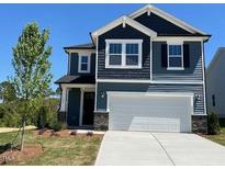 Charming two-story home showcasing a clean white garage door and complemented by tastefully dark blue siding at 106 Little Creek Dr, Lillington, NC 27546