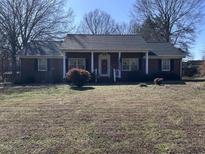 Charming brick home featuring a covered front porch with white columns and a well-maintained lawn at 1926 W Front St, Burlington, NC 27215