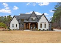 Stunning two-story home featuring a modern farmhouse design with a mix of painted brick and dark accents and manicured landscaping at 299 Seaforth Landing Dr, Pittsboro, NC 27312