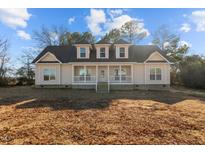 Charming home featuring a welcoming front porch and dormer windows under a blue sky at 406 Stewart Town Rd, Lillington, NC 27546
