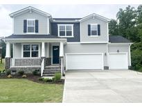 Charming two-story home with a welcoming front porch, two-car garage, and manicured lawn at 456 Barbour Farm Ln, Four Oaks, NC 27524