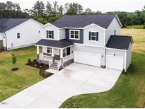 Two-story home showcasing well-manicured lawn, two-car garage, welcoming front porch, and stylish architectural details at 456 Barbour Farm Ln, Four Oaks, NC 27524