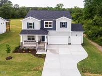Charming two-story home with a welcoming front porch and a well-manicured lawn and a spacious driveway at 456 Barbour Farm Ln, Four Oaks, NC 27524