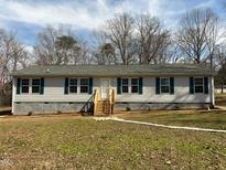 Charming single-story home featuring light siding, green shutters, and a wooden staircase to a bright white front door at 610 Apple St, Gibsonville, NC 27249