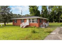 Cozy brick home featuring a well-manicured lawn and charming front entrance with painted white railings at 702 Joyner St, Clayton, NC 27520