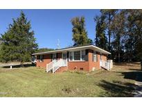 Charming brick home featuring a well-manicured lawn and bright white trim at 702 Joyner St, Clayton, NC 27520
