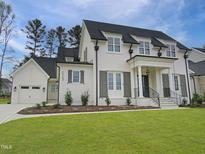 Stunning white brick home with black accents, manicured lawn, and a welcoming front porch at 7723 Roberts Rd, Apex, NC 27523