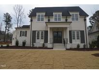 Stately two-story home with brick facade, black shutters, black roof, and manicured lawn at 7723 Roberts Rd, Apex, NC 27523
