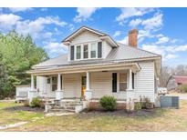 Charming two-story home with a metal roof, yellow front door, and a welcoming front porch at 1373 Tom Stevens Rd, Siler City, NC 27344