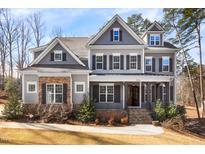 Charming two-story home featuring stone and shingle accents, complemented by a well-manicured lawn and landscaped garden at 198 Gentry Dr, Pittsboro, NC 27312