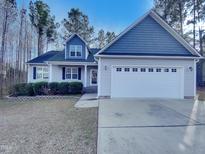 Charming home featuring a two-car garage, blue shingle accents, light gray siding, and well-manicured landscaping at 201 Silver Creek Dr, Clayton, NC 27520