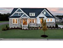 Charming two-story home showcasing stone accents, a covered porch, and manicured lawn at 223 Harvester Rd, Angier, NC 27501