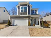 Inviting two-story home showcasing a two-car garage, stone accents, and a charming front porch at 70 Hawksbill Dr, Franklinton, NC 27525