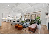 Bright open-concept living room featuring coffered ceilings, fireplace, hardwood floors, and sliding doors to outdoor living space at 7212 Summer Tanager Trl, Raleigh, NC 27614