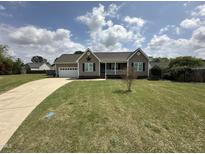 Charming home featuring a manicured lawn and a classic exterior design with an inviting front porch at 106 Bishop Ln, Dunn, NC 28334