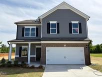 Charming two-story home boasts gray siding, brick accents, and a spacious two-car garage, all under a clear blue sky at 106 E Victory View. Ter, Smithfield, NC 27577