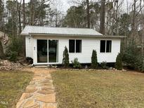 Charming single story home with stone walkway and metal roof, surrounded by mature trees and landscaping at 117 Lone Star Dr, Louisburg, NC 27549