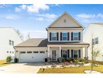 Charming two-story home with a well-manicured lawn and inviting front porch seating area at 1311 Arena Ln, Fuquay Varina, NC 27526