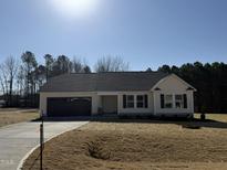 Charming one-story home featuring a spacious yard, attached garage, and a classic, inviting facade at 145 Magnolia Run Way, Benson, NC 27504