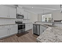 Bright kitchen boasts stainless appliances, granite countertops, white cabinetry, and wood flooring at 25 Bourne Dr, Franklinton, NC 27525