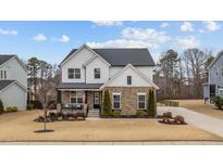 Charming two-story home with a stone and white siding exterior and manicured lawn at 3012 Freeman Farm Way, Rolesville, NC 27571