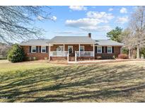 Charming brick home featuring a welcoming front porch and well-maintained lawn at 6480 Union Ridge Rd, Burlington, NC 27217