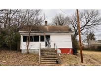 Shows the front of a white house with a small porch and several steps leading up to the front door at 1106 Proctor St, Durham, NC 27707
