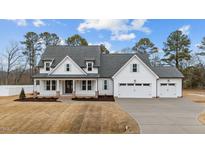Beautiful two-story home boasts a three car garage and a charming front porch at 120 Lane Farms Way Way, Holly Springs, NC 27540