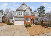 Beautiful two-story home featuring a brick and siding exterior, attached garage, and manicured landscaping at 132 Mystic Pine Pl, Apex, NC 27539