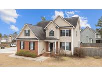 Charming two-story home featuring tan siding, red brick accents, and black shuttered windows at 18 Orangewood Court Ct, Lillington, NC 27546