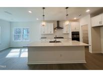 Bright, modern kitchen with stainless steel appliances, pendant lighting, and a large kitchen island at 3287 Roundly Rd # 13, New Hill, NC 27562