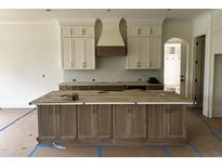 Spacious kitchen island featuring modern cabinetry and hardware, complemented by custom hood vent and upper cabinets at 395 Meadow Walk Dr, Fuquay Varina, NC 27526