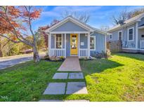 Charming blue home with a bright yellow front door and a walkway leading to the porch at 518 Worth St, Raleigh, NC 27601