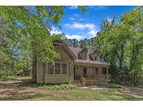 Rustic cabin-style home with a cozy front porch and lush green surroundings, perfect for peaceful living at 1031 Wait Ave, Wake Forest, NC 27587