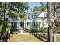 Charming two-story home with a white exterior, black shutters, and manicured landscaping at 10560 Arnold Palmer Dr, Raleigh, NC 27617