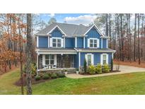 Charming two-story home with a blue exterior, covered front porch, and landscaped yard at 130 Willow Bend Dr, Youngsville, NC 27596