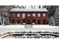 Stunning two-story brick home featuring a symmetrical facade, wreaths, and snow-covered landscaping at 1612 Hunting Ridge Rd, Raleigh, NC 27615
