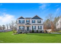 Two-story home features a manicured lawn, neutral siding, and a covered front porch at 594 Executive Dr, Lillington, NC 27546